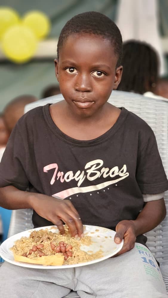 A boy holding a plate of rice and beans