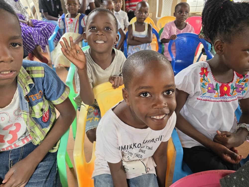 Children smiling and waving during a gathering